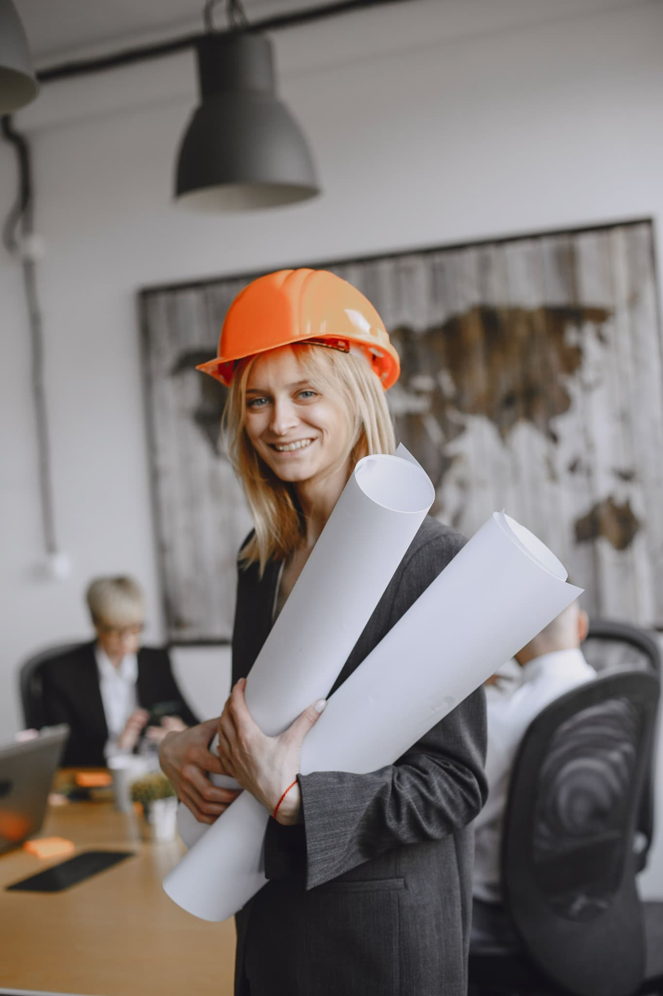 An architect or construction professional holding rolled plans in an office