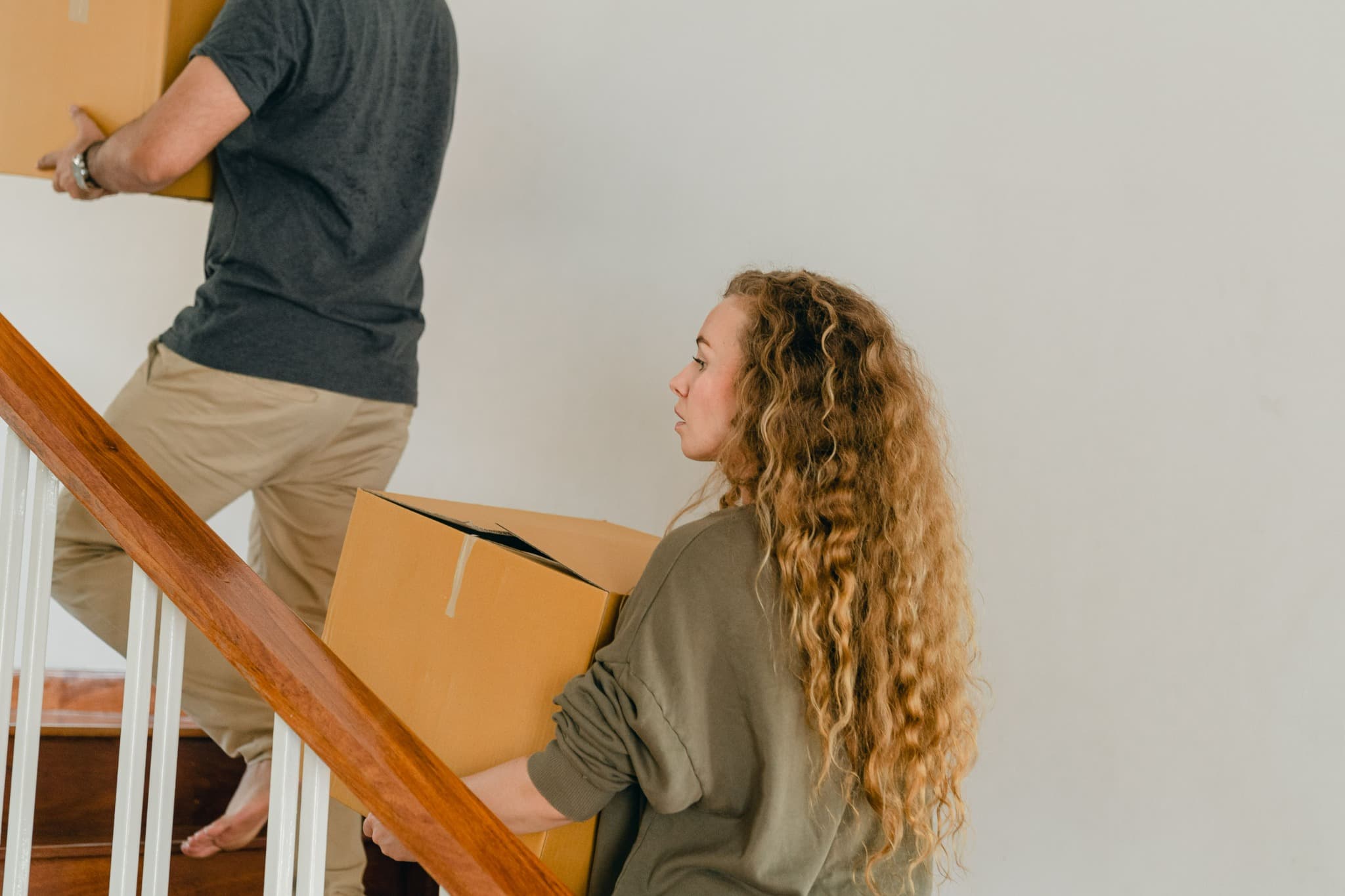 People carrying moving boxes into a home